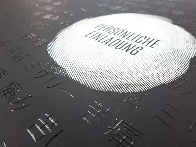 Event invitation with tactile UV gloss varnish and white print on black uncoated cardboard - detailed view