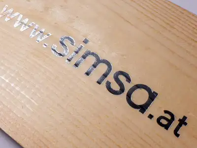 Beschriftung mittels Heißfolienprägung Silber auf Holzplatte