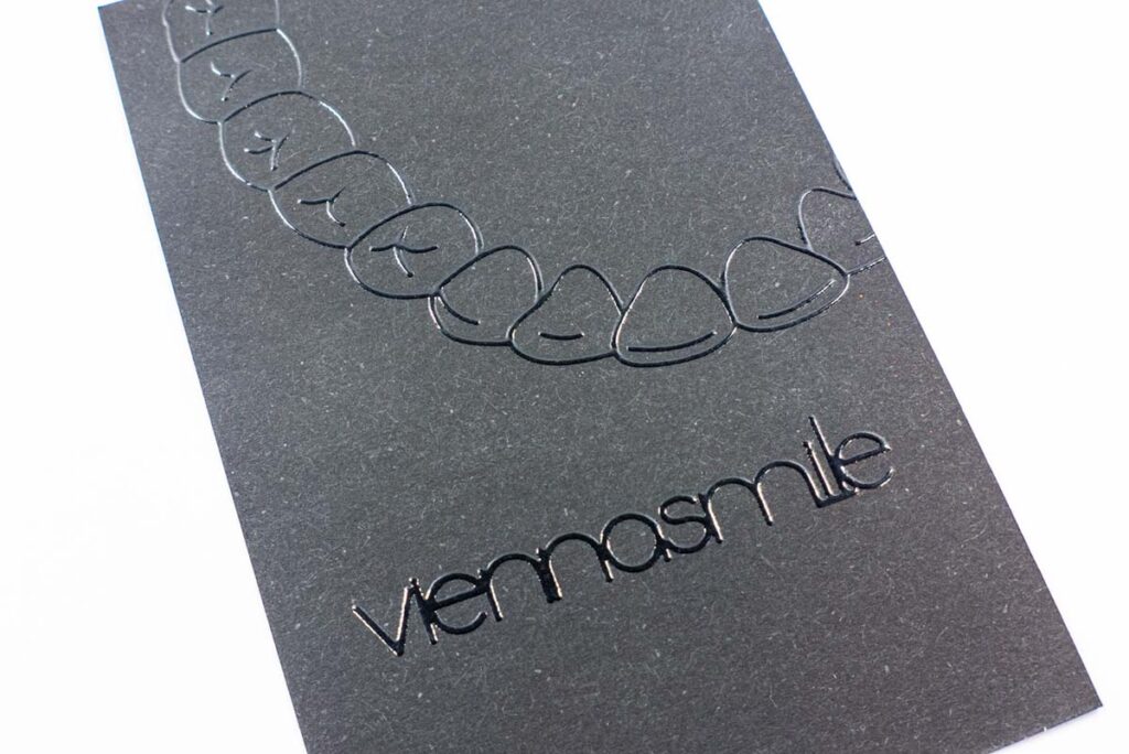Visitenkarte mit Text und Logo aus UV-Glanzlack auf schwarzem Naturpapier
